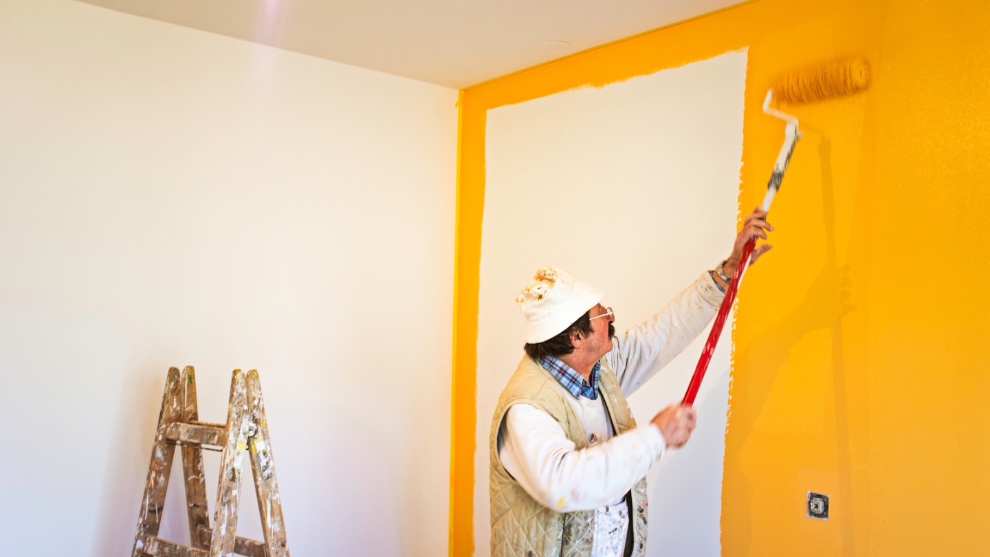 Pintura interior profesional - Pintores trabajando en una pared naranja